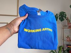 working artist not starving artists. Fun original shirt designed to encourage artists! ⭐Divinely Inspired by rainbows 🌈 sunshine 🌞 and the simple truth that God created us to create, therefore if you are making art , you're a working artist doing God's work :)  🎁A gift that's easy and simple: - Perfect gift idea for any creative person or artist (painter, illustrator, singer, musician, music producer, actor, writer, poet, dancer, performing artist, art teacher, painting professor, choir director, youtuber, content creator etc. ) in your life who appreciates graphic tee shirts.  👕A statement t-shirt that's eye catching and minimal: - a simple but powerful and encouraging message 💛 A fun design that's meaningful, bright and colorful.  💛 Limited edition run, only 7, so get yours today! Teacher Painting, Branded Merch, Artist Merch, Working Artist, Art Tshirts, Puff Vinyl, Mexican Artwork, Choir Director, Creative Department