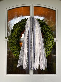 a wreath with ribbons hanging on the side of a glass door that is covered in plastic