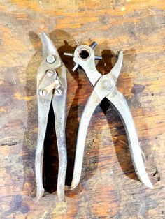 two pairs of pliers sitting on top of a wooden table