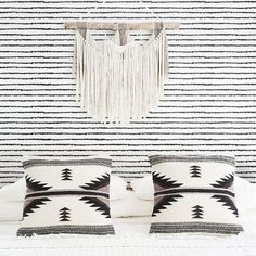 two black and white pillows sitting on top of a bed next to a wall hanging