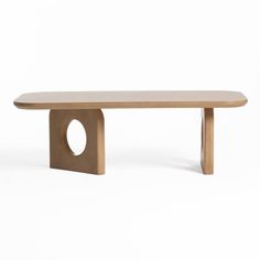 a wooden bench sitting on top of a white floor next to a table with an oval hole in the middle