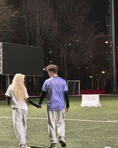 a man and woman walking across a soccer field