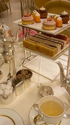 a table topped with plates and cups filled with desserts next to a tea pot