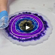 a person is working on an art project with purple and blue swirls in the center