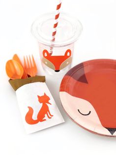 an orange and white paper plate next to a cup with a fox design on it