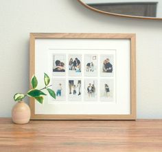 a wooden table topped with a framed photo next to a vase filled with a plant