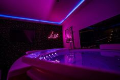 a bathtub in the middle of a room lit up with purple light and neon lights