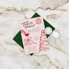 a pink and green christmas party card on top of a marble table