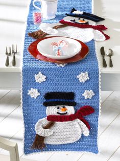 a crocheted table runner with a snowman on it and a plate in the middle