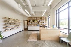 the inside of a store with lots of shelves and plants on display in front of large windows