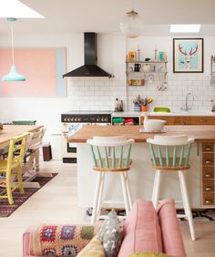 two stools in front of a kitchen island with three chairs and a stove top oven