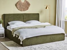 a bed with white pillows and green headboard