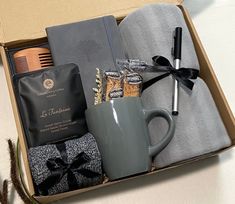 an open box containing a coffee cup, tea bag and other personal care items on a table