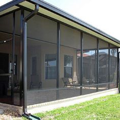 an enclosed patio area with glass walls and sliding doors on the side of the house