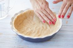 two hands reaching into a pie crust in a bowl