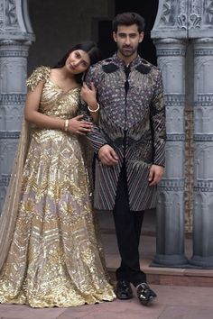 a man and woman standing next to each other in front of an ornate building with columns