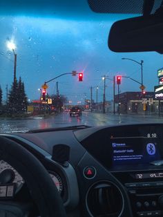 the dashboard of a car on a city street with traffic lights in the background at night