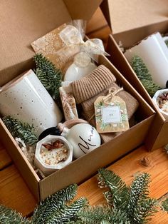 two boxes filled with coffee mugs sitting on top of a wooden table next to pine branches