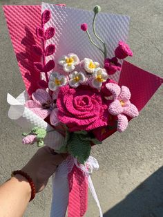 a person holding a pink and white bouquet with flowers on it's side,