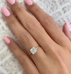 a woman's hand with pink manicured nails and a diamond ring