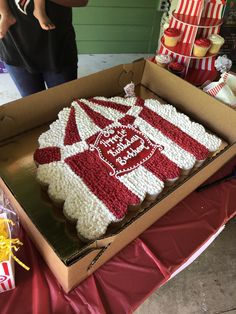 a large cake in a box on top of a red and white table cloth covered table