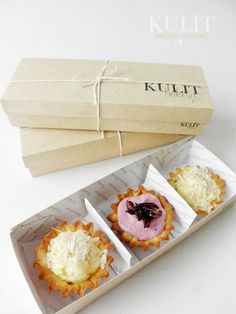 three small pastries sitting in a box next to each other on a white surface