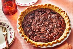 a pecan pie sitting on top of a table next to plates and utensils