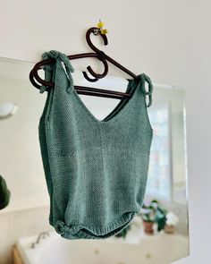 a green sweater hanging from a hook in a bathroom