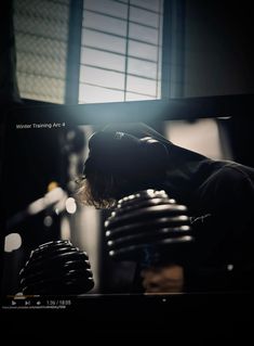 a man sitting in front of a tv holding a pair of dumbbells and looking at the screen