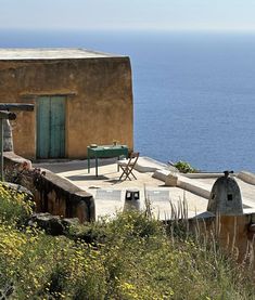 an outdoor table and chairs on the side of a building with water in the background