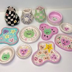 there are many plates and cups that have faces on them, including one with a frog