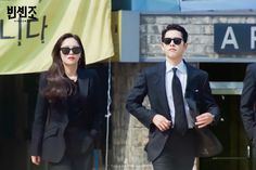 two people in suits and sunglasses walking down the street