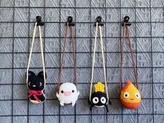 four small stuffed animals hanging from hooks on a wall