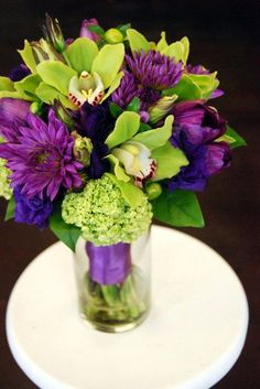 a vase filled with purple and green flowers