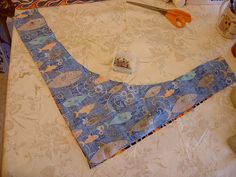 a piece of fabric is laying on top of a table with scissors and other crafting supplies