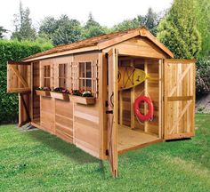 a wooden shed sitting on top of a green grass covered field next to a red life preserver