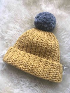 a yellow and blue knitted hat laying on top of a white rug