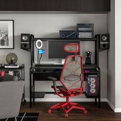 a desk with a chair, computer monitor and speakers on it in a living room