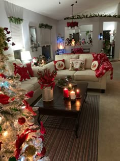 a living room decorated for christmas with red and white decorations on the couches, coffee table