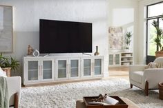 a living room with white furniture and a flat screen tv