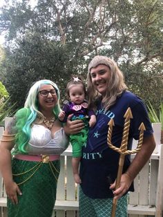 two people dressed up as mermaids and one is holding a baby