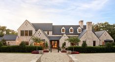 a large brick house with lots of windows and plants in front of the entrance to it