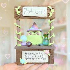 a hand holding up a small wooden shelf with a sign on it that says potions and crystals