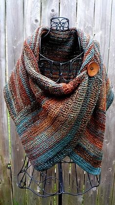 a knitted shawl with buttons on it sitting on top of a metal stand