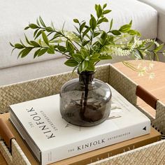 a glass vase filled with flowers sitting on top of a book next to a white couch