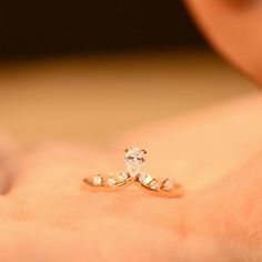 a close up of a person's hand holding a ring with a diamond on it