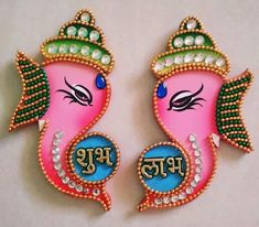 two pink and green ganeshi shaped brooches with pearls on them, sitting next to each other