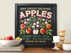 an old fashioned apple sign is displayed on a table next to some candles and apples