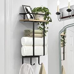 a bathroom with towels and plants on the shelf in front of the mirror, next to a potted plant