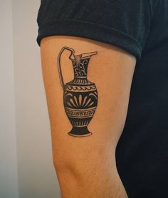 a man with a tattoo on his arm has a black and white vase in it